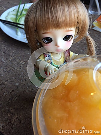 An adorable BJD ball joint doll) and orange juice Editorial Stock Photo